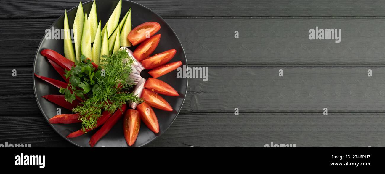 Platter of assorted fresh vegetables on black background. Banner. Stock Photo
