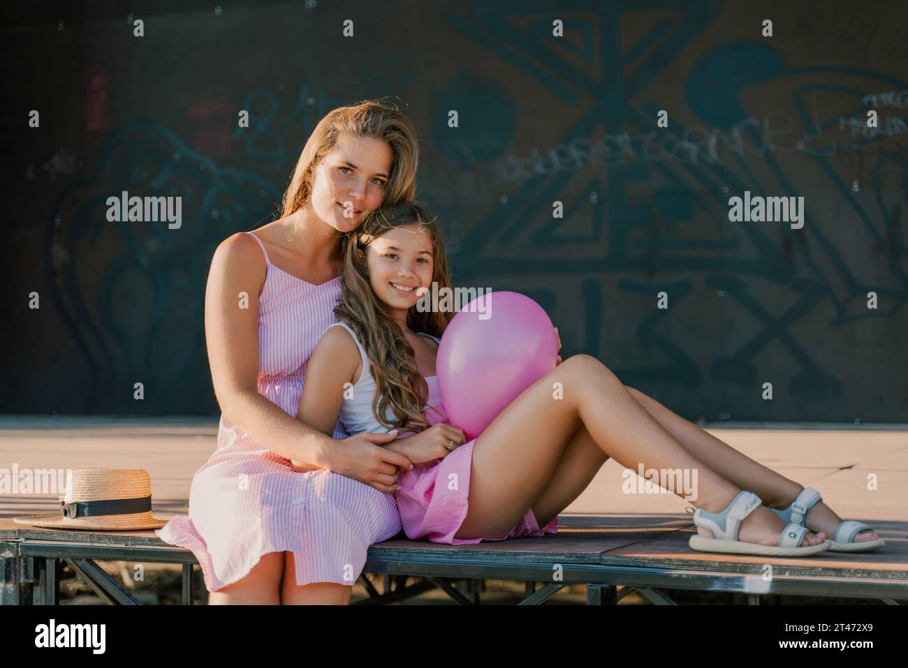Portrait of mother and daughter in pink dresses with flowing long hair ...