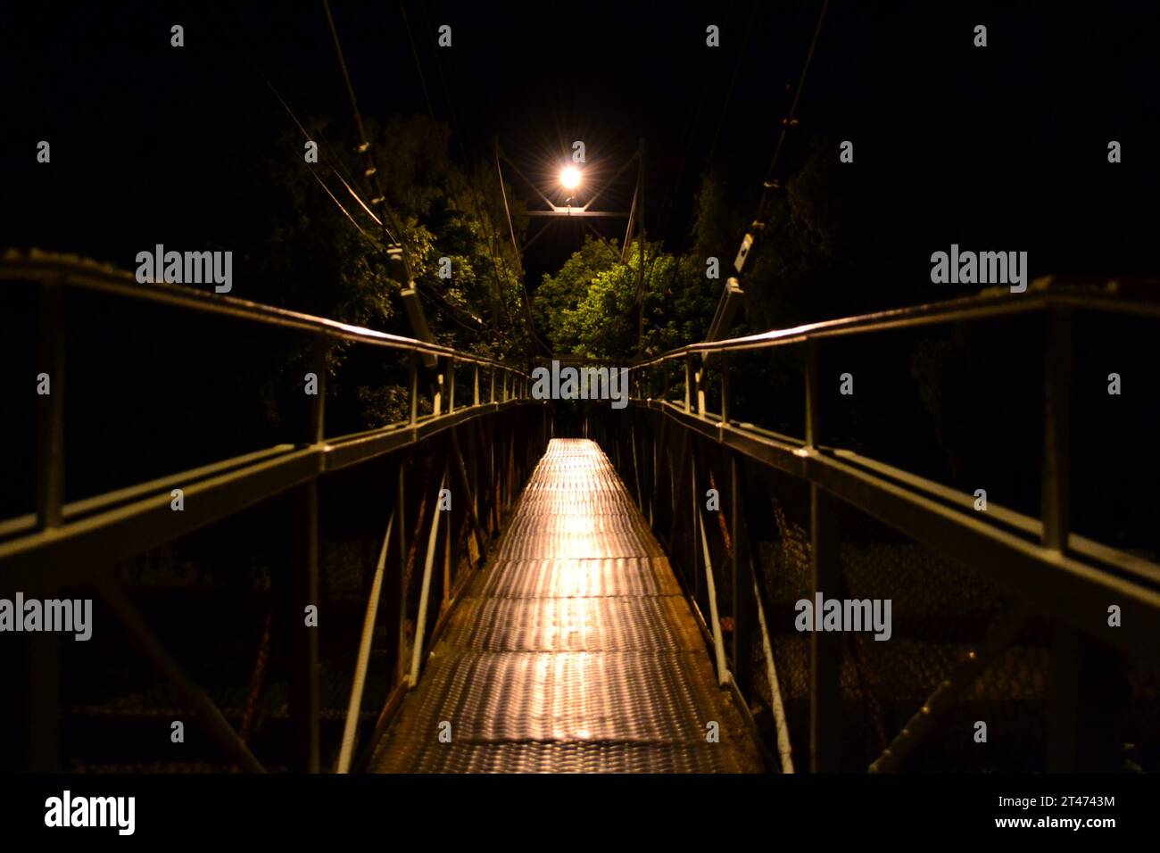 A bridge illuminated by multiple lights at night. Stock Photo