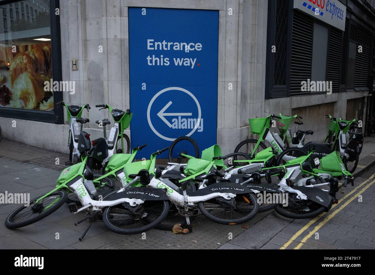 Abandoned Lime electric bicycles, left in a heap outside a Tesco Express convenience store along the Strand, central London, England, United Kingdom Stock Photo