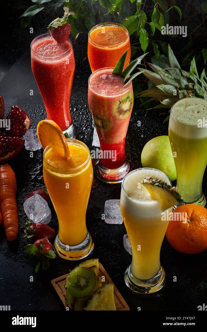 A picture of several cups of various natural juices on a black