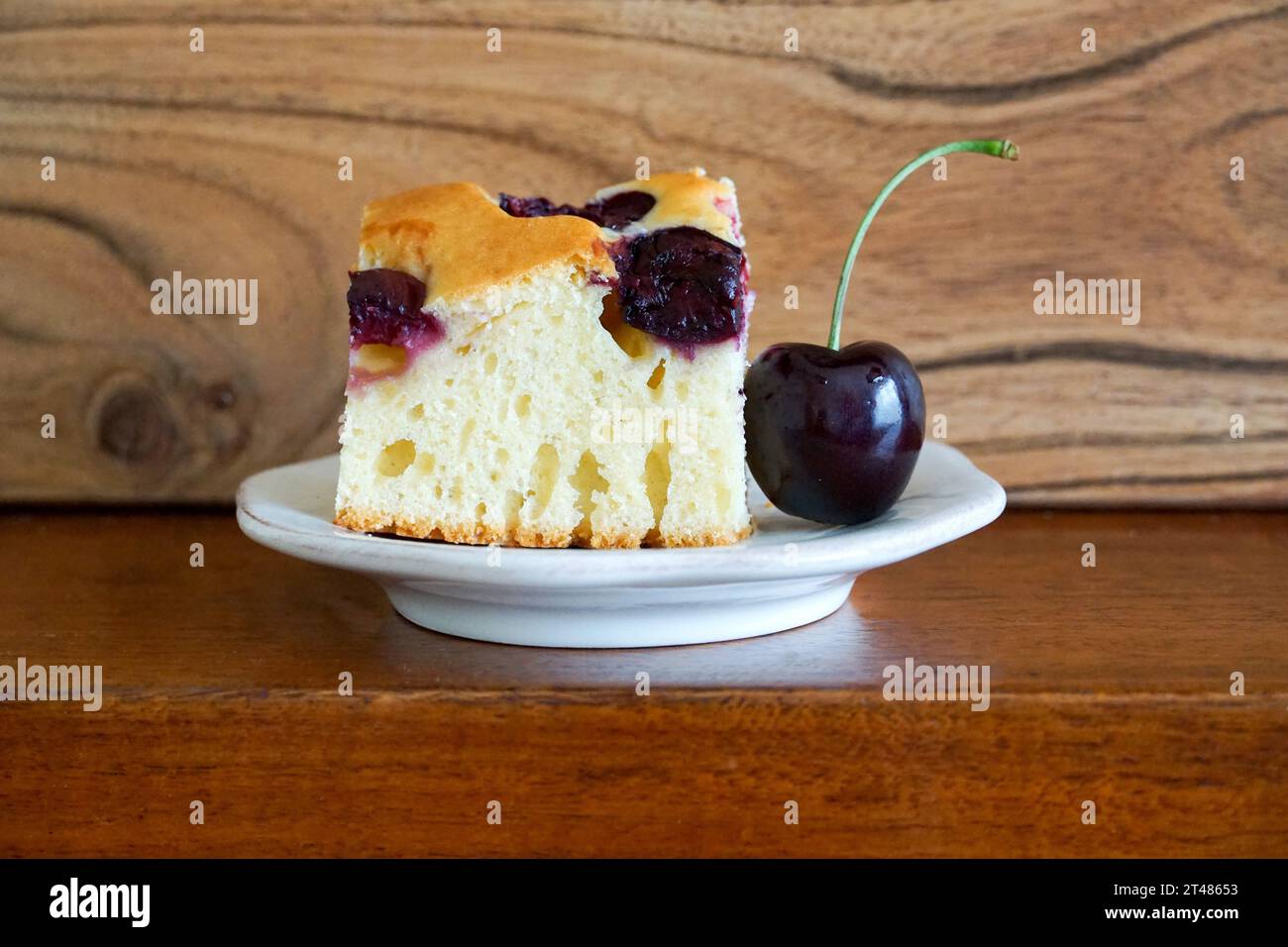 Cherry cake on white plate and wooden background. Selective focus. Stock Photo