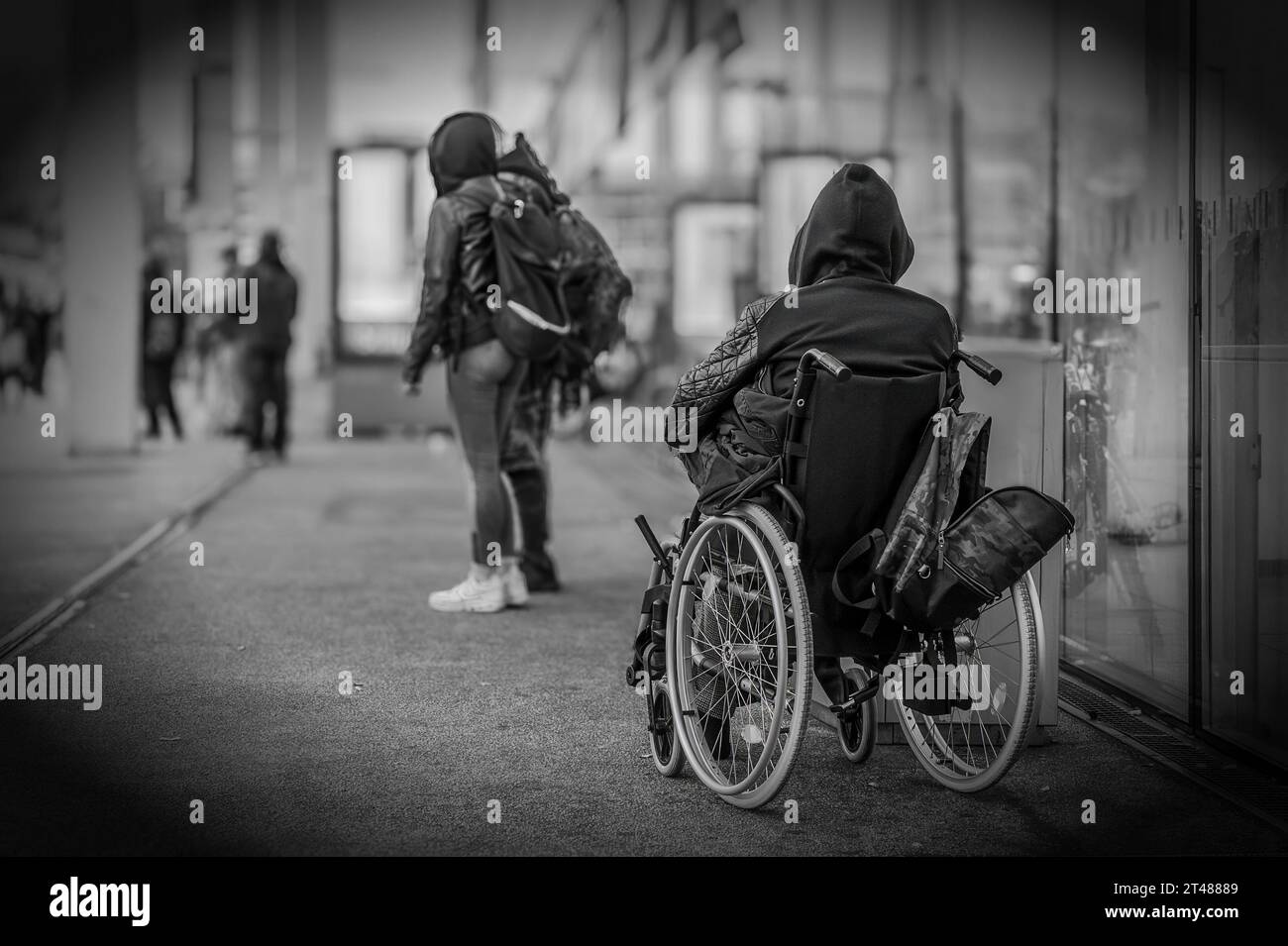 A homeless man in a wheelchair in front of a public building Stock