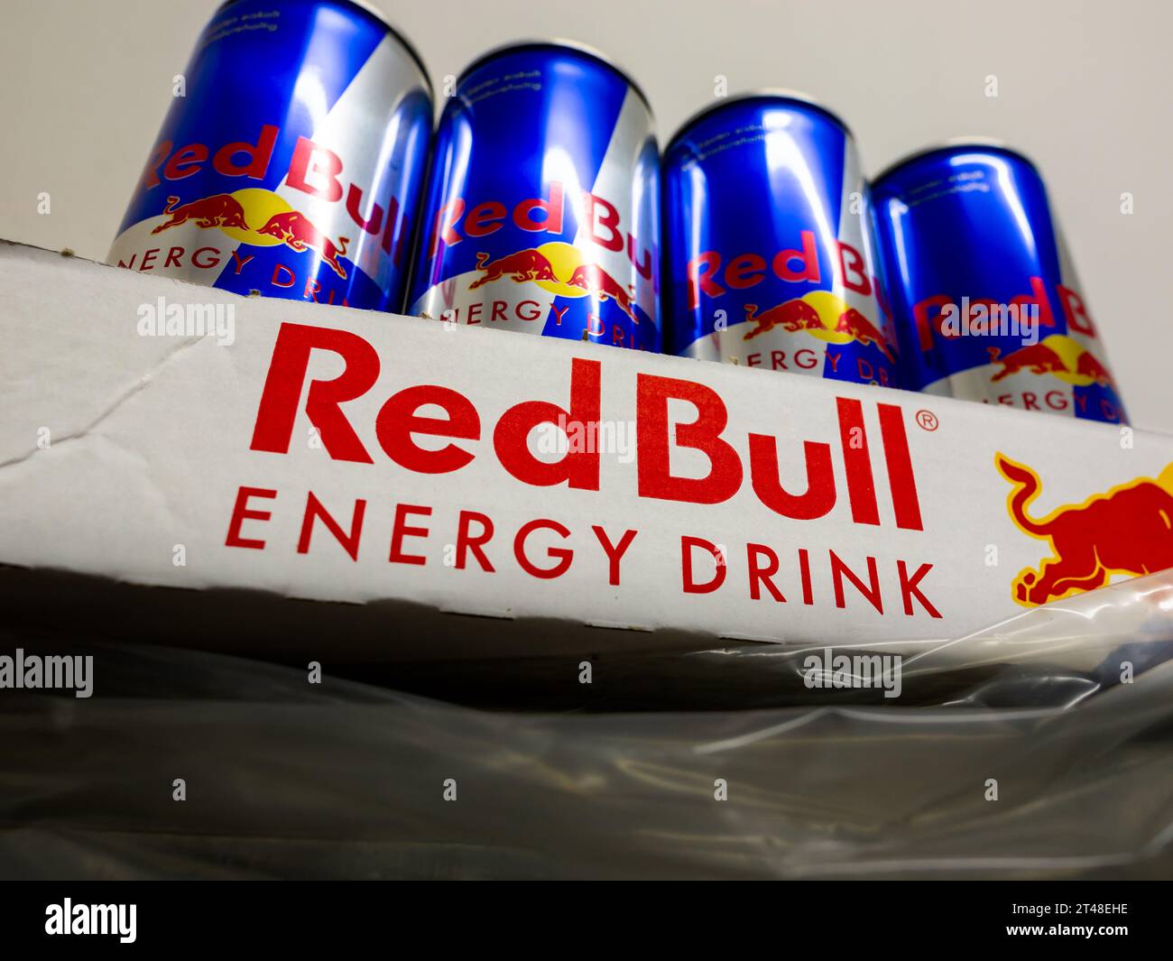 Red Bull energy drink cans in a tray on a shelf. The lifestyle beverage is sweet and with caffein. The logo sign of the company is on the packaging. Stock Photo