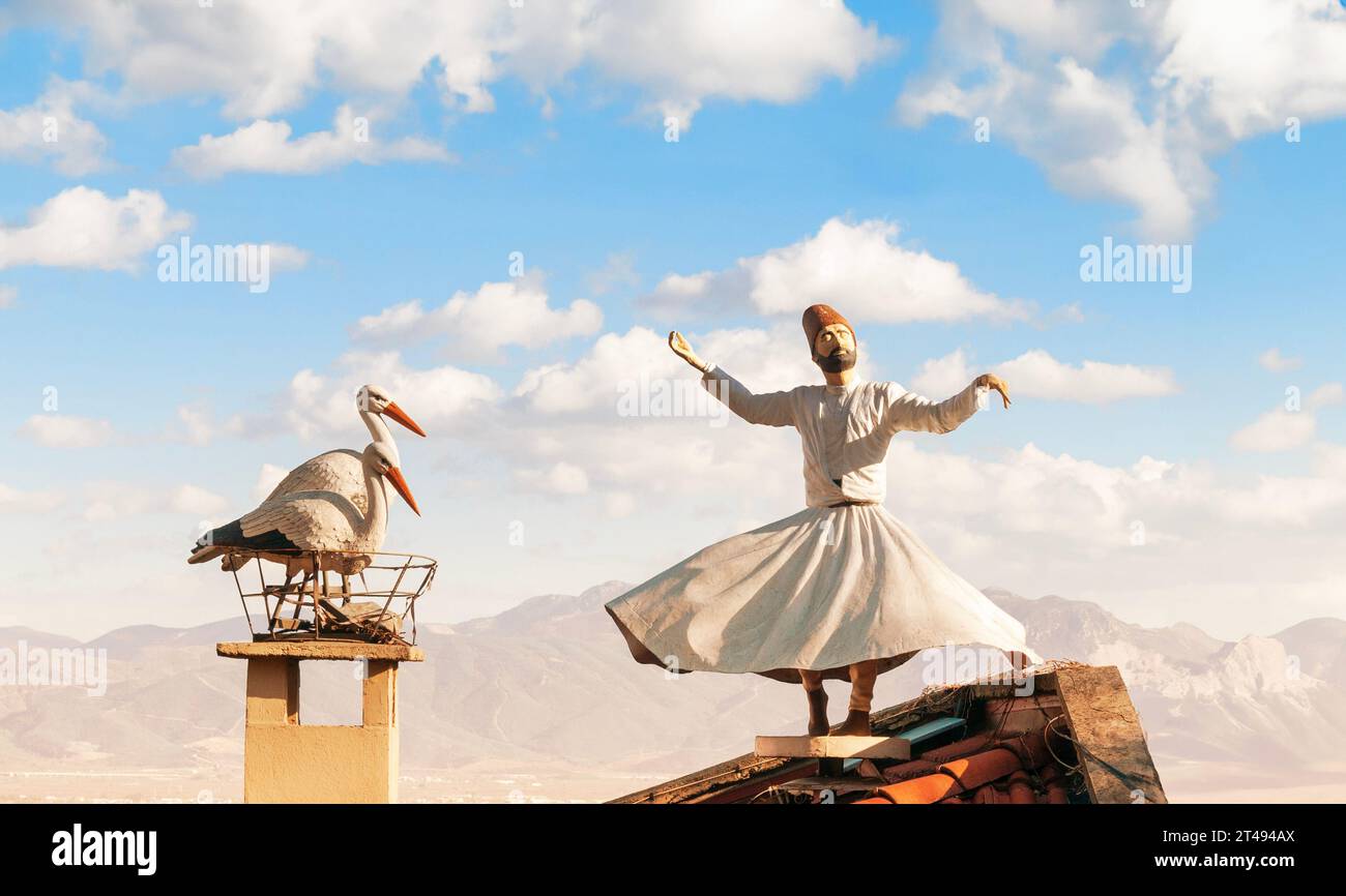 Statue of a dervish in a trance, spinning on the roof of a house with a stork statue next to it. Stock Photo