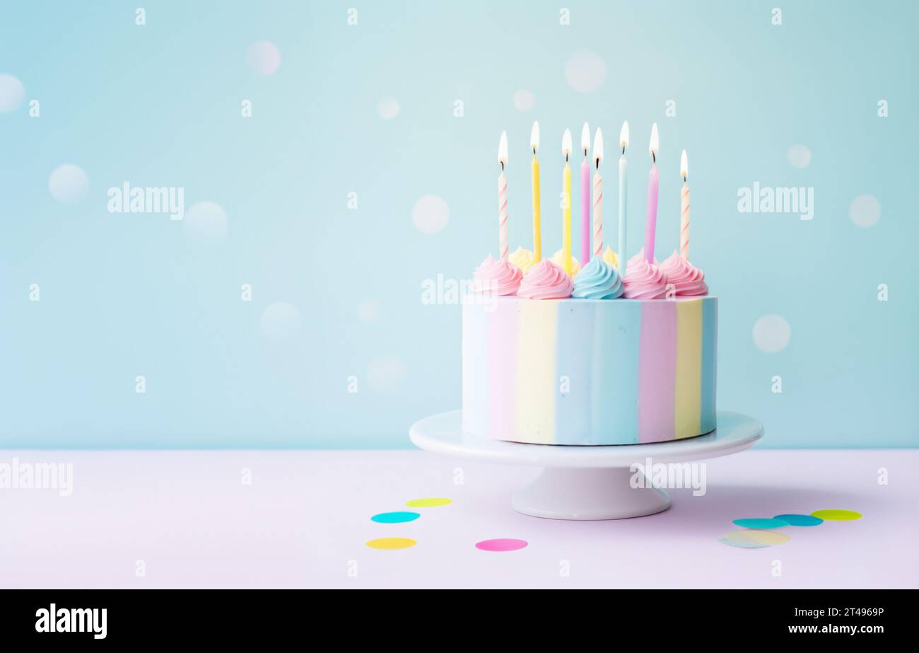 Birthday cake decorated with pastel colored buttercream and eight birthday cake candles against a pastel background Stock Photo