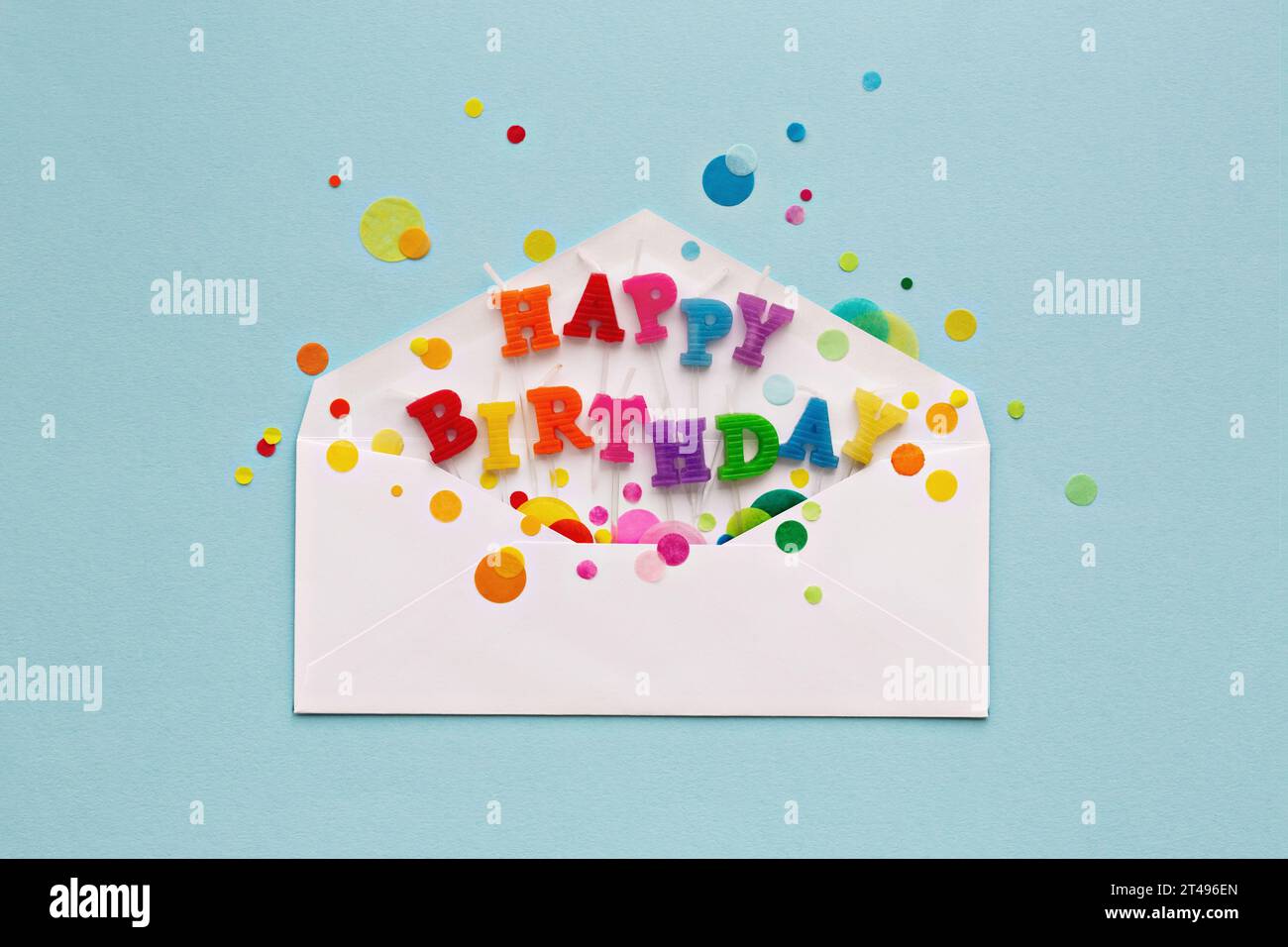 Birthday card envelope with colorful happy birthday candles and rainbow colored celebration confetti, overhead view Stock Photo