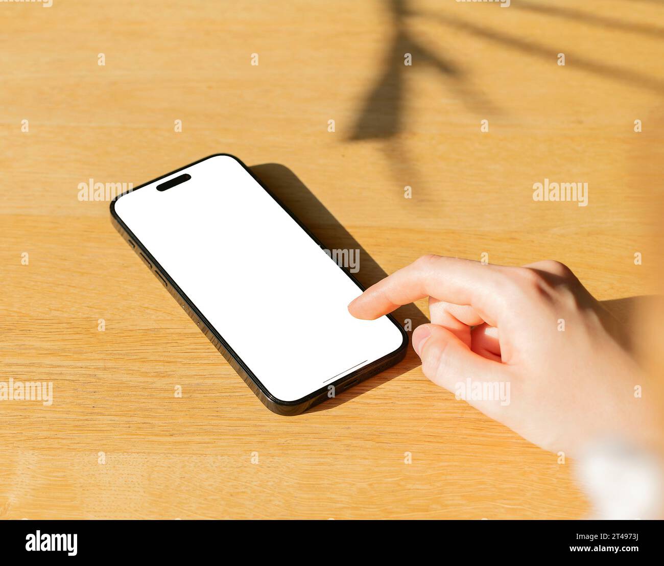 Berlin, Germany October 20 2023 Finger clicking, tapping on mobile phone screen mock up, display mockup on wooden table Stock Photo
