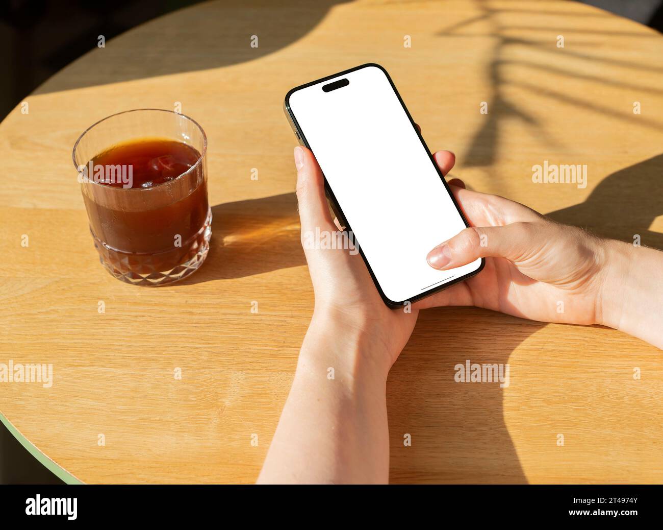 Berlin, Germany October 20 2023 Finger clicking, tapping, using mobile screen mock up, coffee glass on table Stock Photo