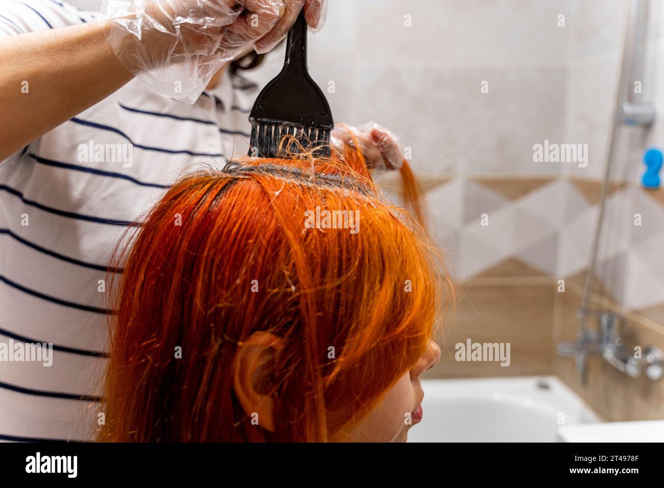 Profile of a pretty teenage girl coloring her hair red. The process of dyeing hair red. Style