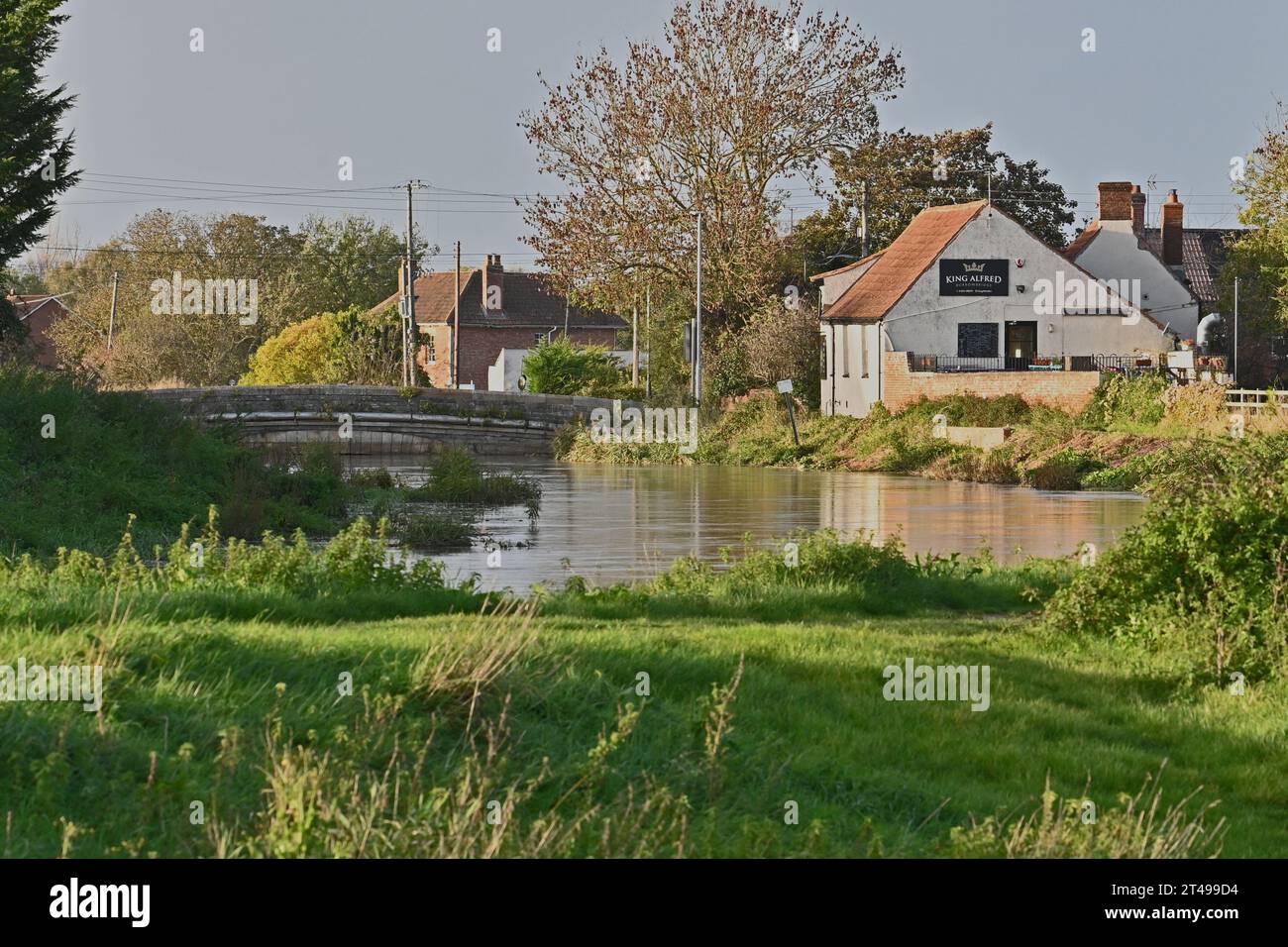 UK Weather. On a mild afternoon a lone walker is seen strolling alongside the River Parrott a village in England, where the the river just reaches the top of the road bridge arch. Picture Credit Robert Timoney/AlamyLiveNews Stock Photo