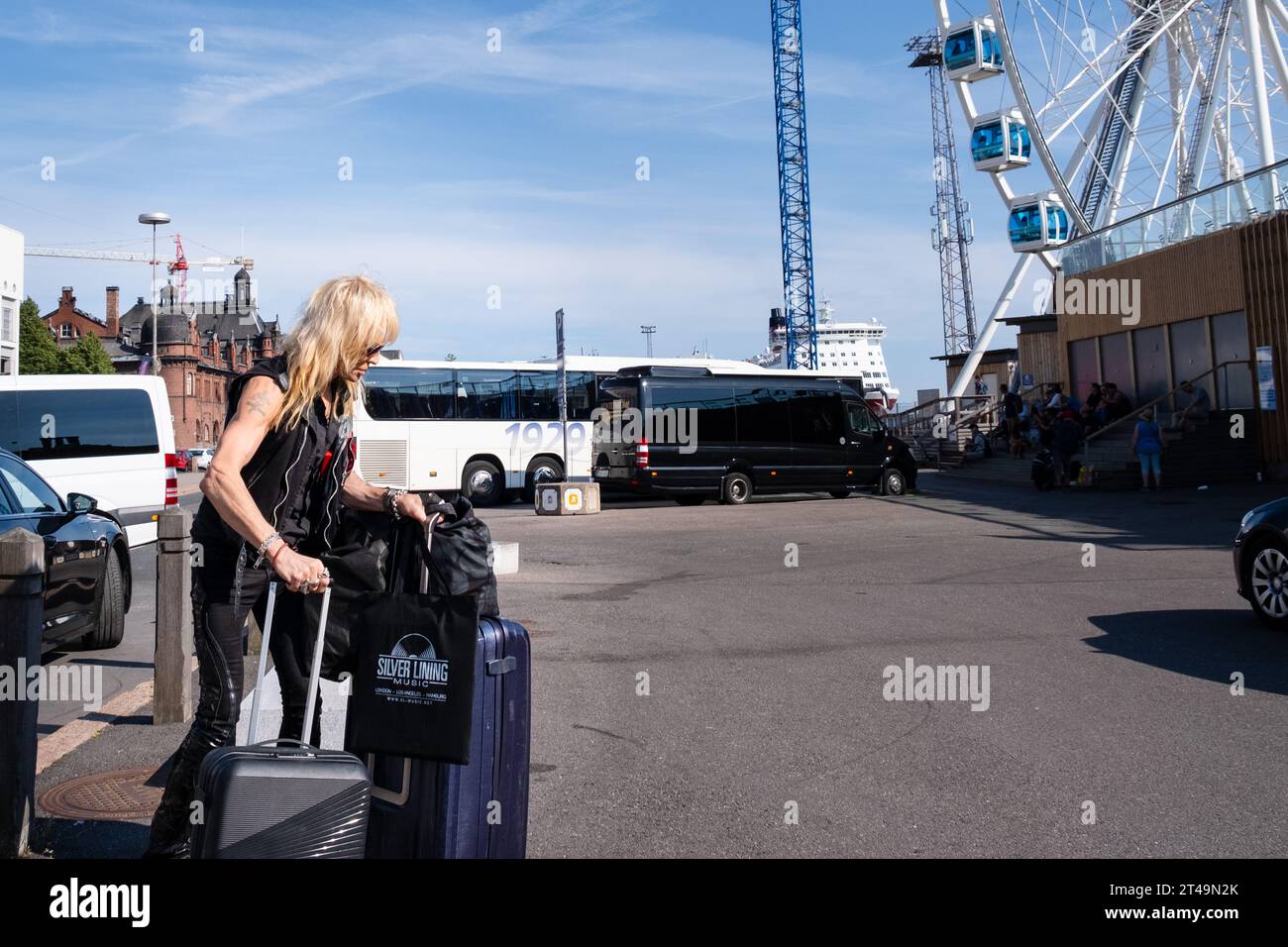 Finnish heavy metal icon Michael Monroe from Hanoi Rocks exits a taxi with suitcases and a vinyl record bag in summer in central Helsinki, Finland. Stock Photo