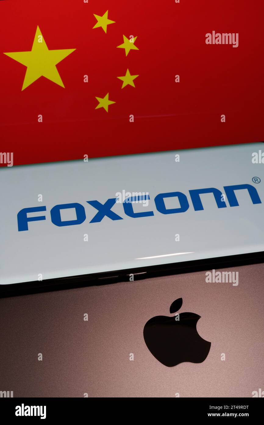 Apple logo seen on IPad, Iphone manufacturer  FOXCONN logo on smartphone and blurred flag of China at the background screen. Concept. Stafford, United Stock Photo