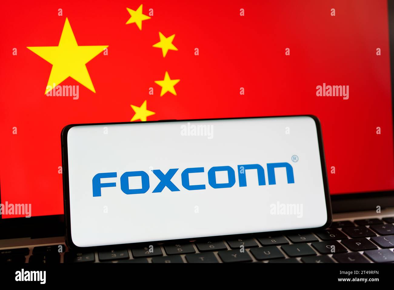 Iphone manufacturer  FOXCONN logo on smartphone and blurred flag of China at the background screen. Concept. Stafford, United Kingdom, October 29, 202 Stock Photo