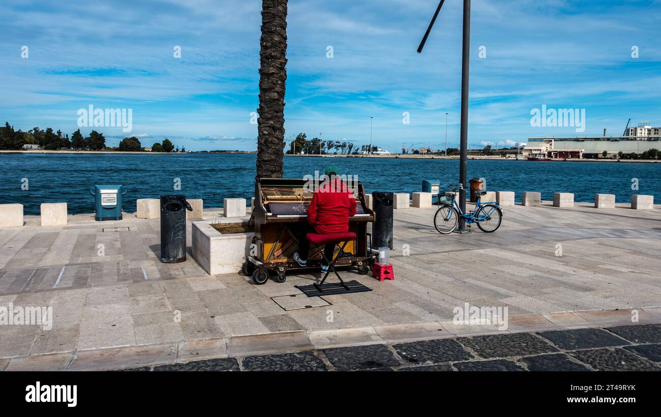 On the seafront in Brindisi, Italy a man busking playing a piano. Stock Photo