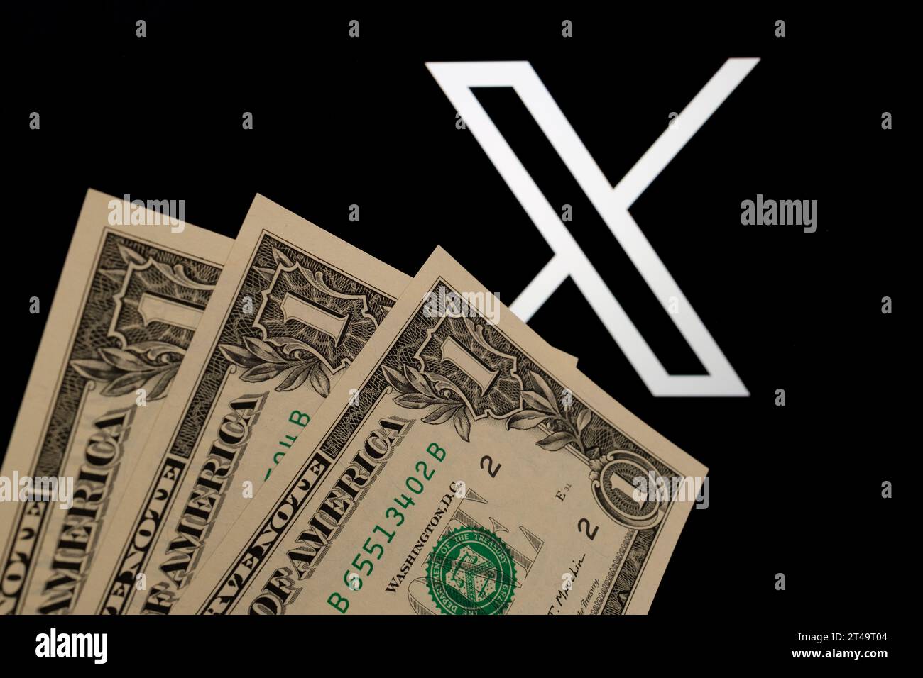 3 US Dollars in front of blurred X social media platform logo (ex Twitter). Concept for new three dollar subscription plan. Stafford, United Kingdom, Stock Photo