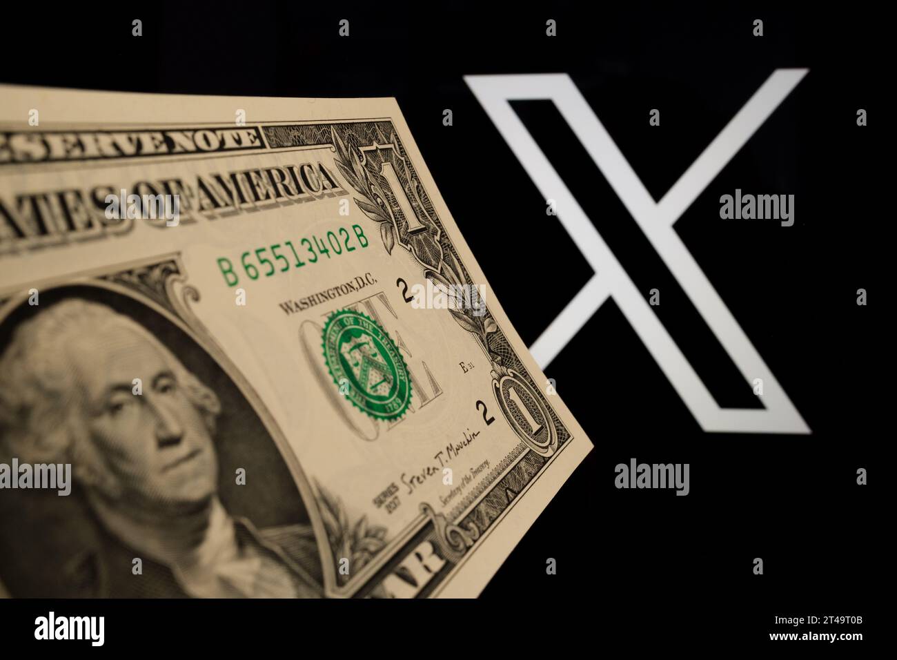 1 dollar banknote in front of blurred X social media platform logo (ex Twitter). Concept for a paid subscription plan. Stafford, United Kingdom, Octob Stock Photo