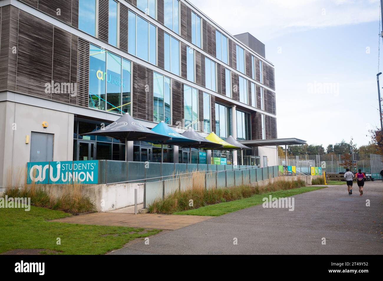 Rear view of joggers running past ARU Student Union building , Anglia Ruskin University, Chelmsford, Essex Campus, Britain, UK. Stock Photo