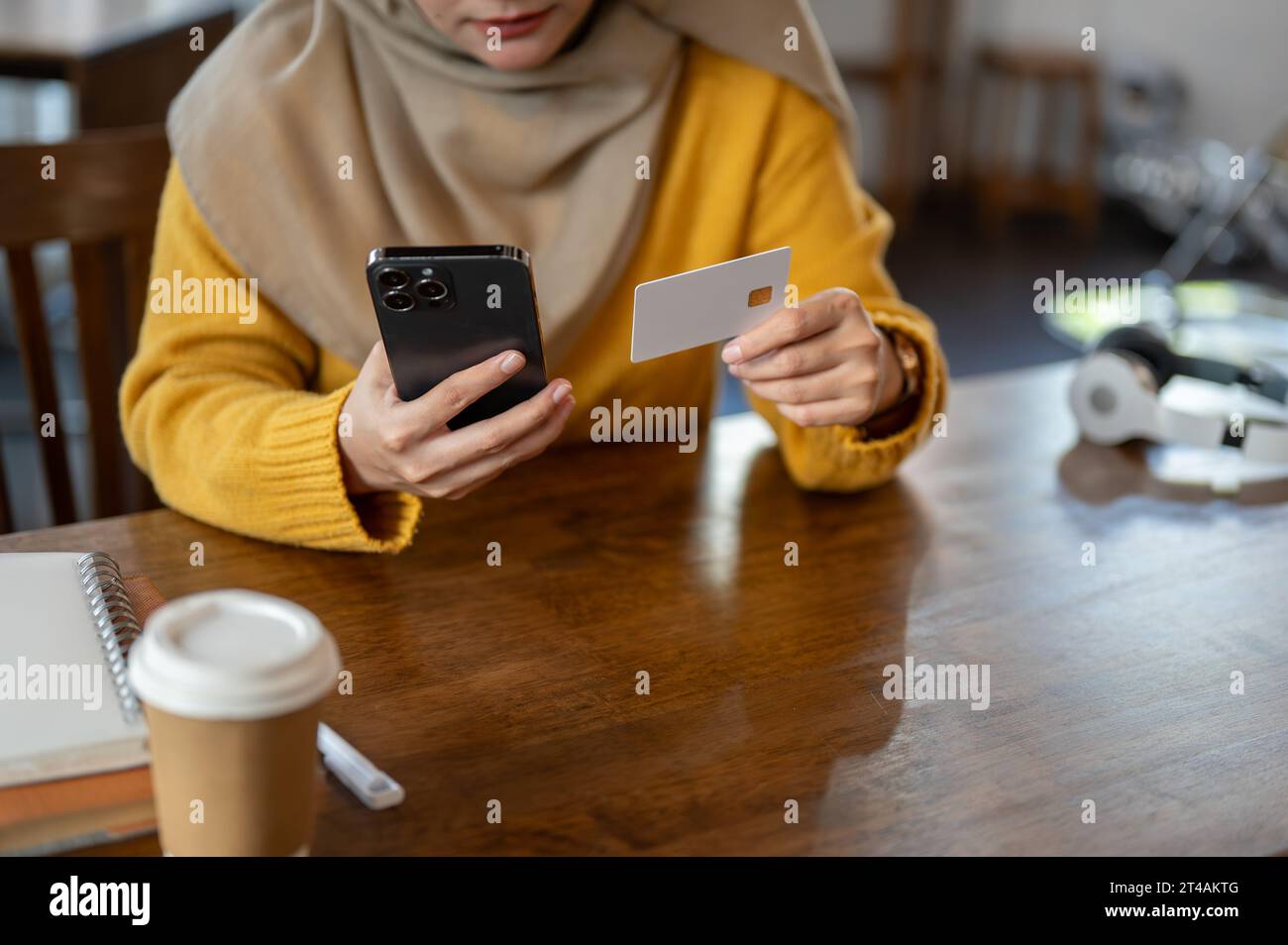 Cropped image of a happy Asian-Muslim woman using her mobile banking application to pay her online bills or registering her credit card with an online Stock Photo