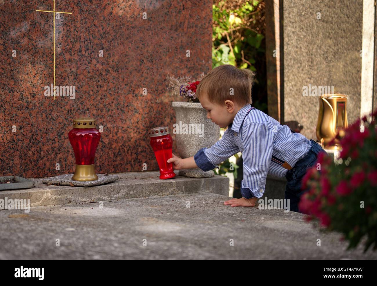 Little toddler holding a candle on the grave Stock Photo