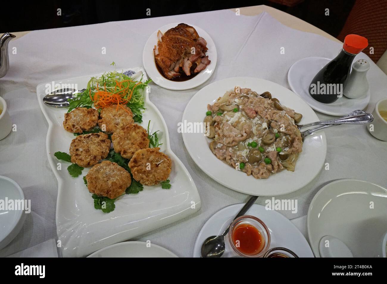 Assorted Chinese food- Stir fry pork noodle with black soy sauce served with Deep fried fish cake and roasted honey duck Stock Photo