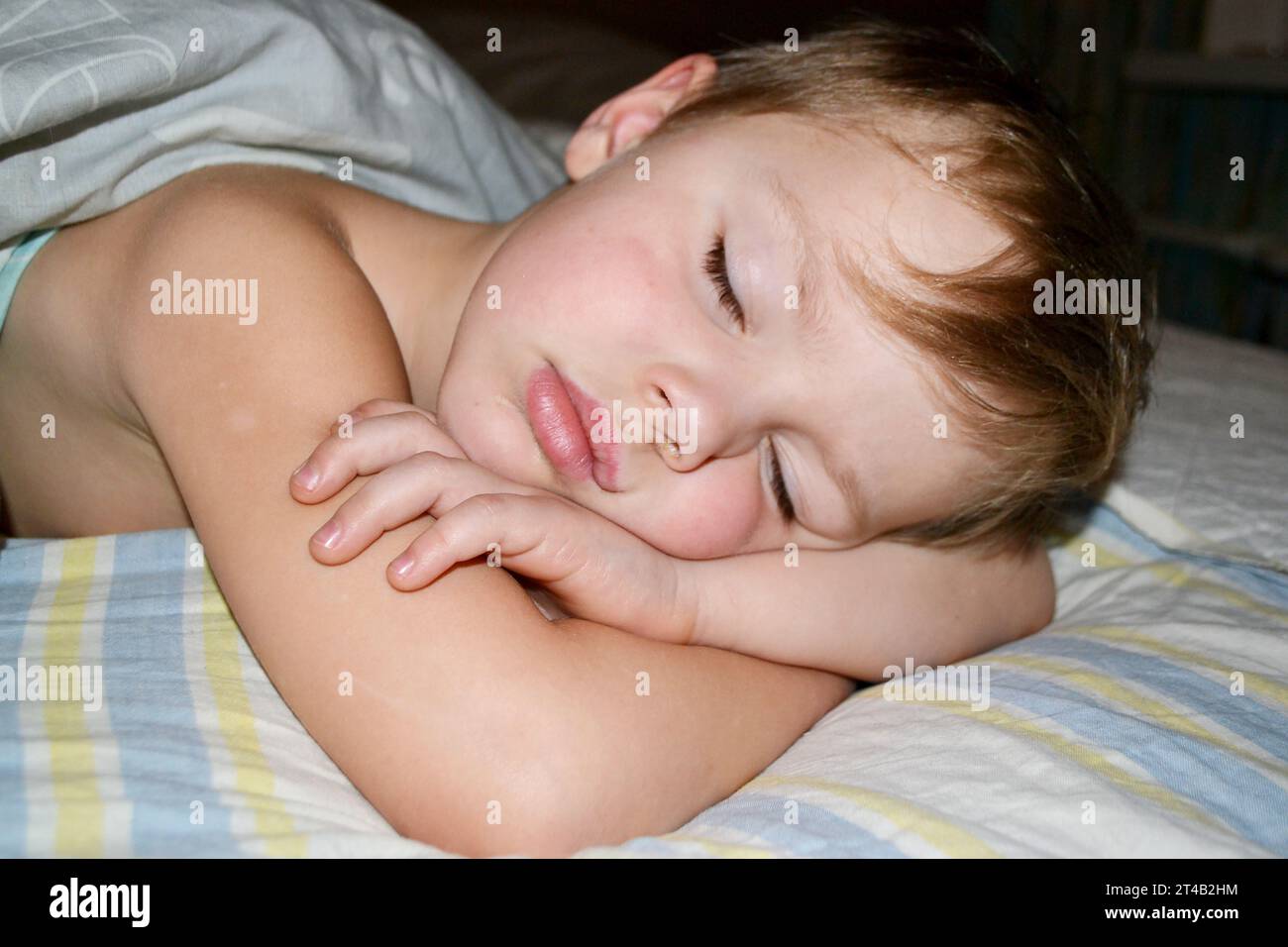 Five years old child sleeping in bed on pillow with a teddy giraffe. High quality photo Stock Photo