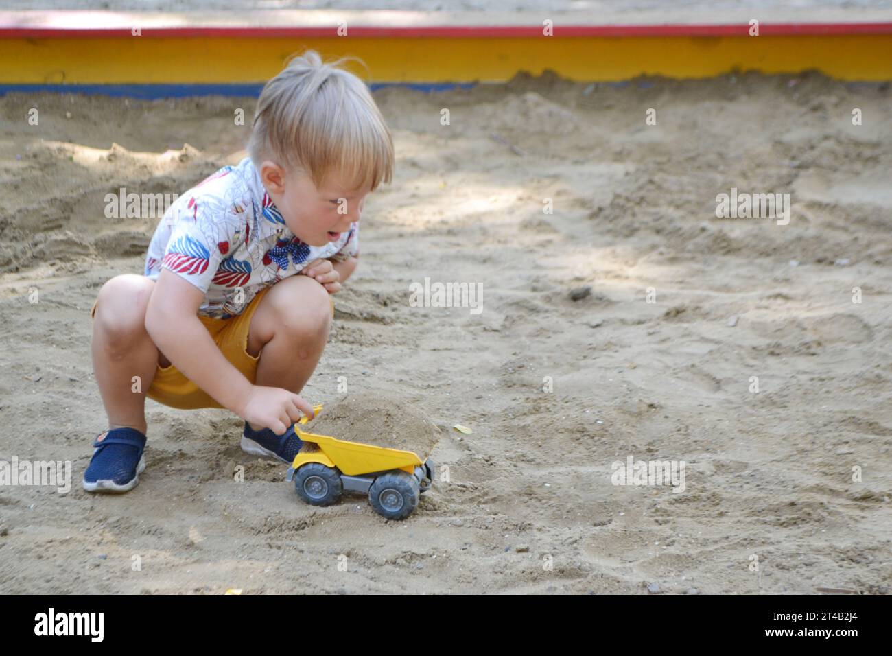 Cute toddler boy playing in sand on outdoor playground. Beautiful baby having fun on sunny warm summer day. High quality photo Stock Photo