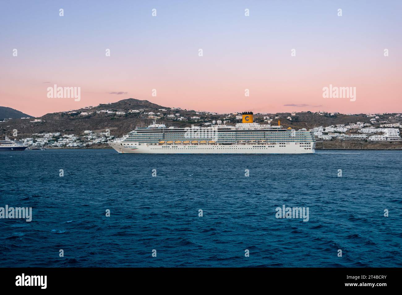 Mykonos, Greece - September 12, 2022: Cruise ship Costa Deliziosa of Costa Cruises at dusk in harbor of Mykonos, Greece. Side view. Stock Photo