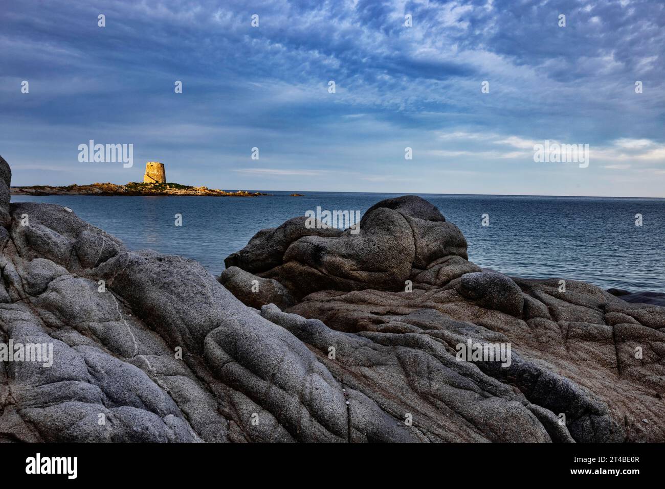 Bizarre rock formations on the beach in front of the Torre di Bari Sardo in the evening light, historic Spanish watchtower from the 16th century Stock Photo