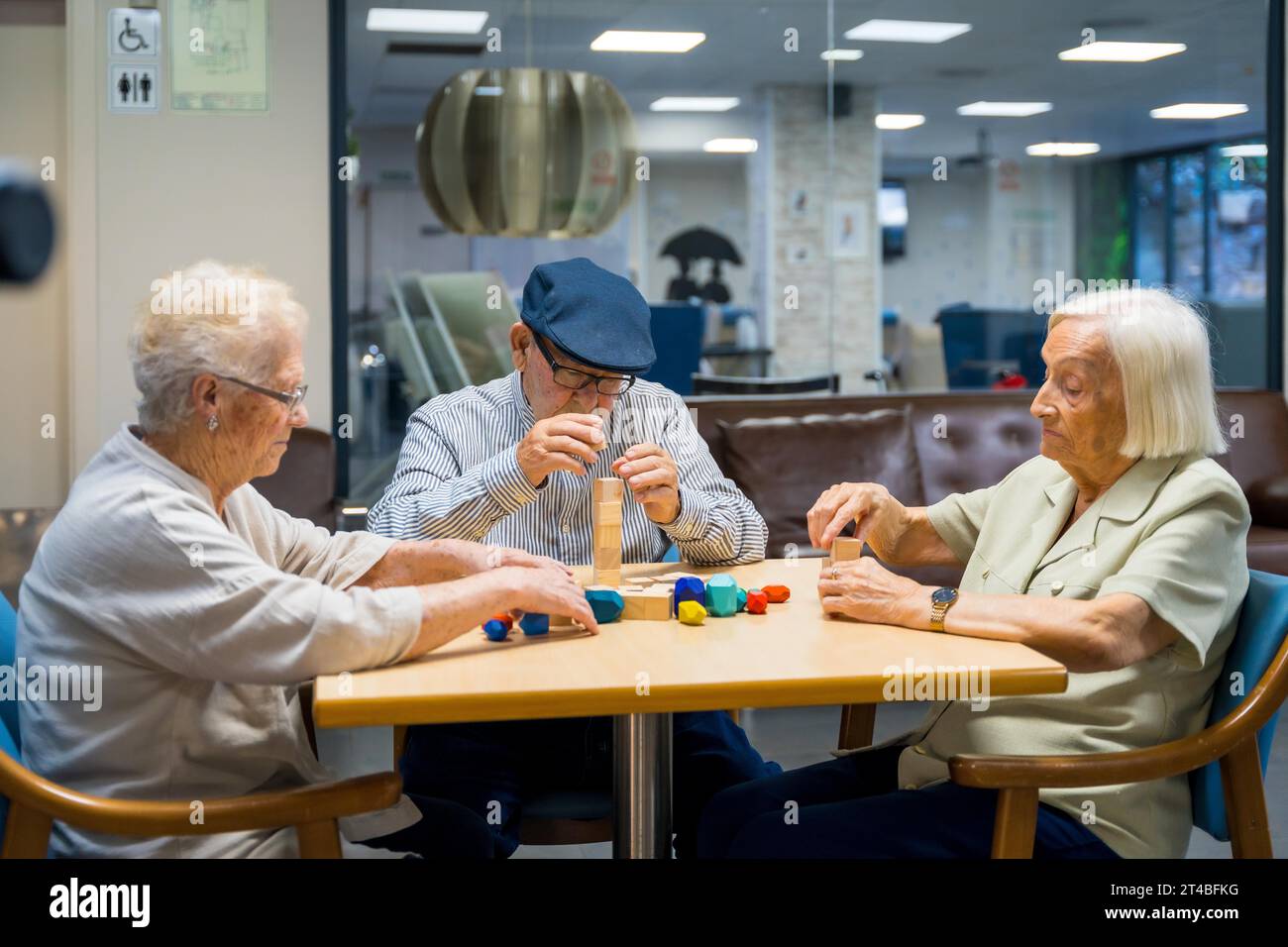 Elderly residents in a nursing home engaging in motor skills games with pieces Stock Photo