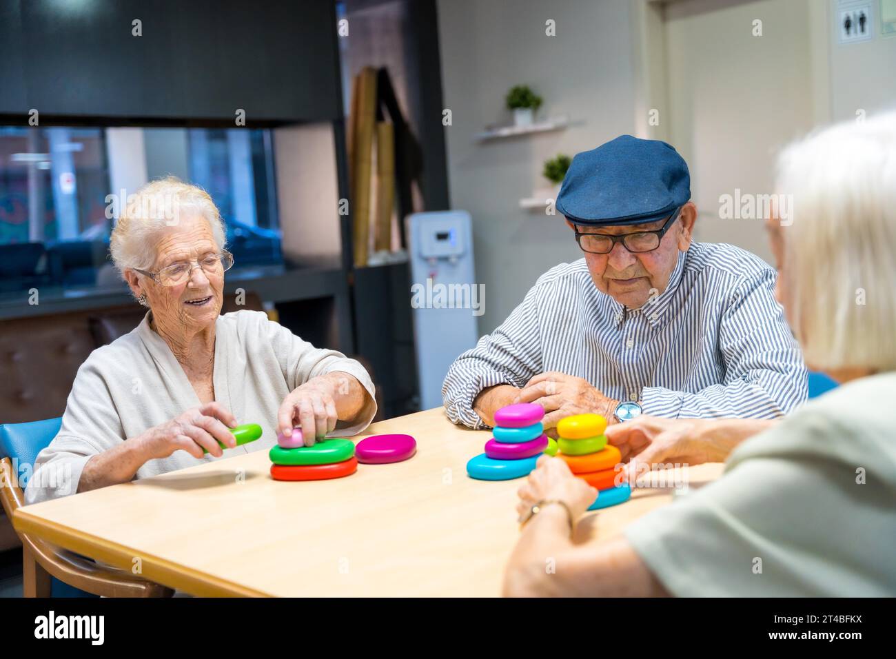 Three cute elder people playing skill games together in a nursing home Stock Photo