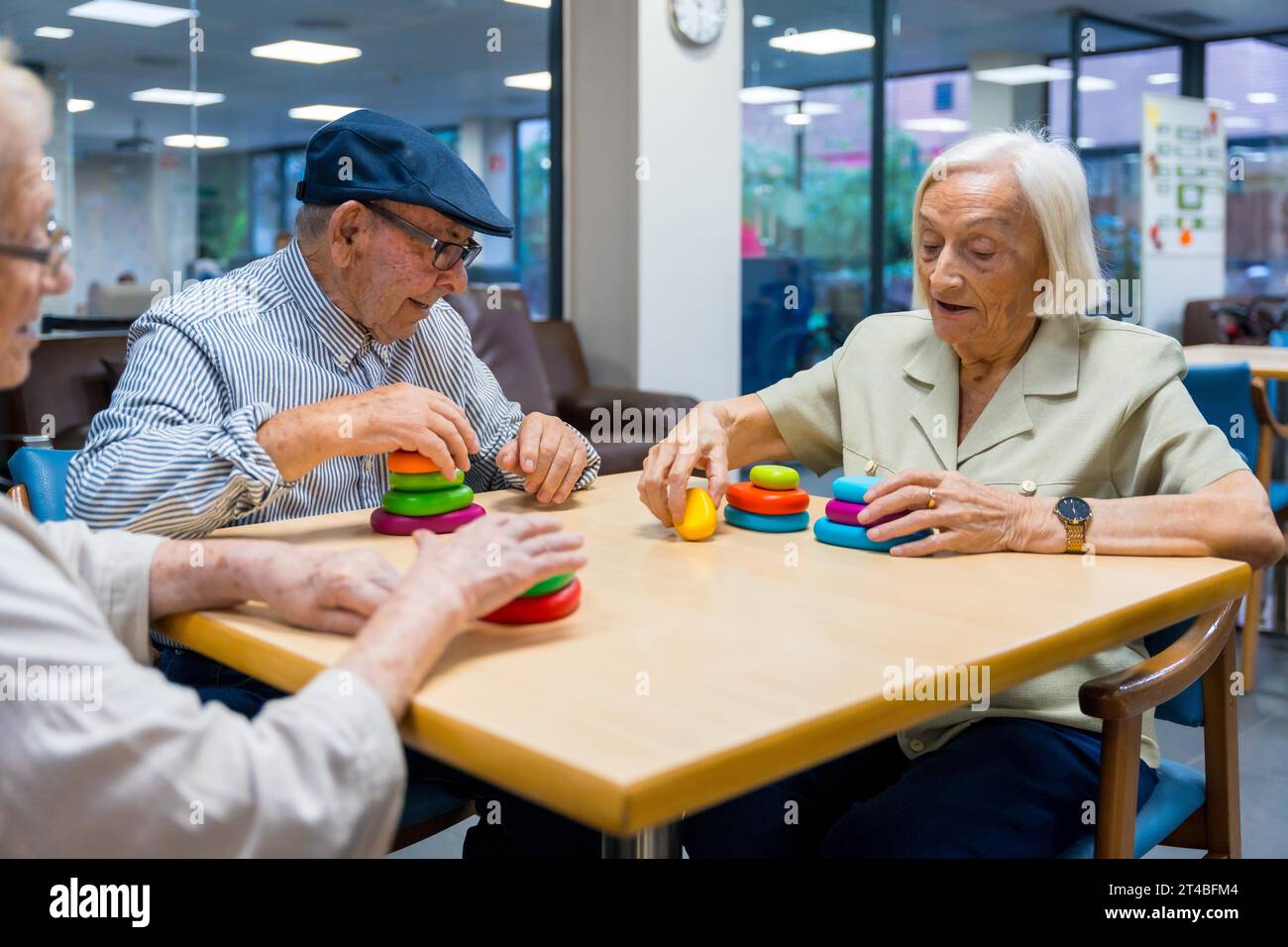 Aged people in a nursing home sharing skills games sitting on a table together Stock Photo