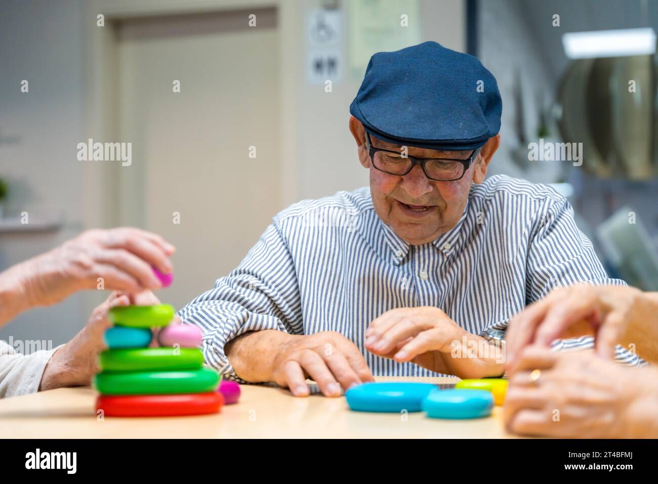 Elder man playing skill games in a nursing home next to mates Stock Photo