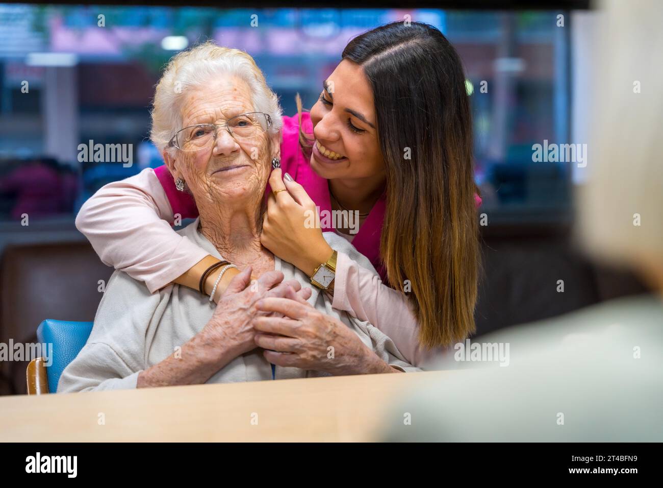Tender moment of a happy nurse caressing and embracing an old woman in a geriatric Stock Photo
