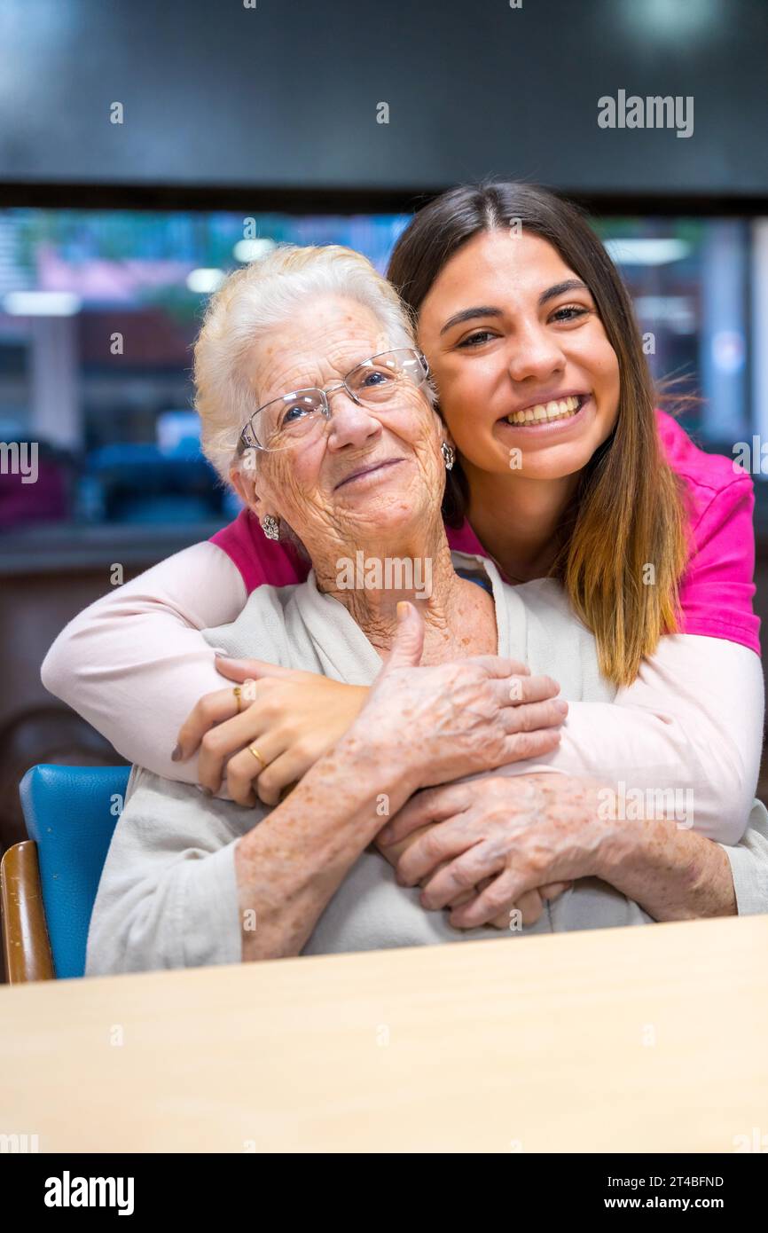Vertical portrait of a cute nurse and an elder woman in a geriatric Stock Photo