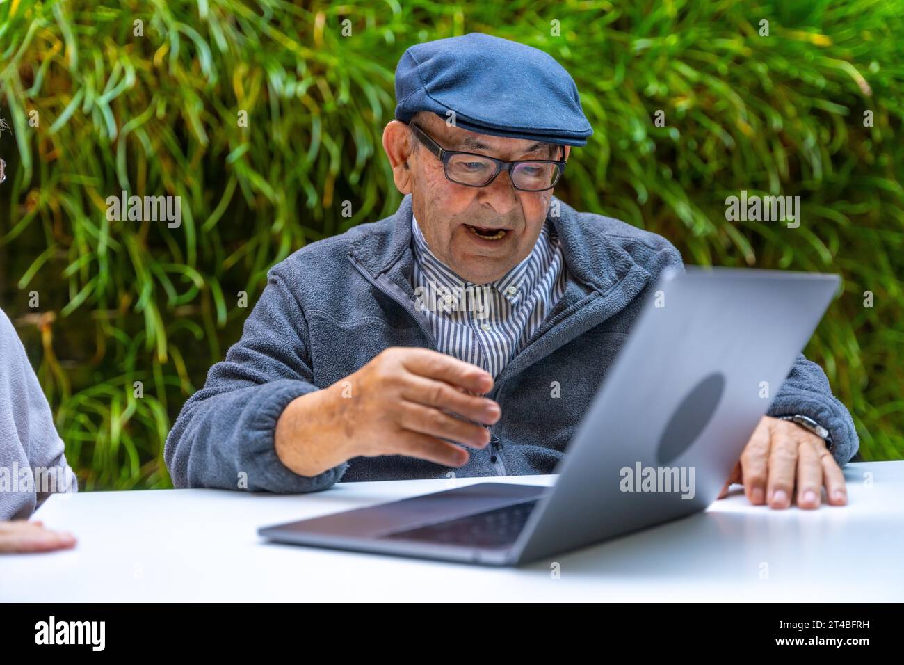 Retired old man using laptop in a garden of a nursing home Stock Photo