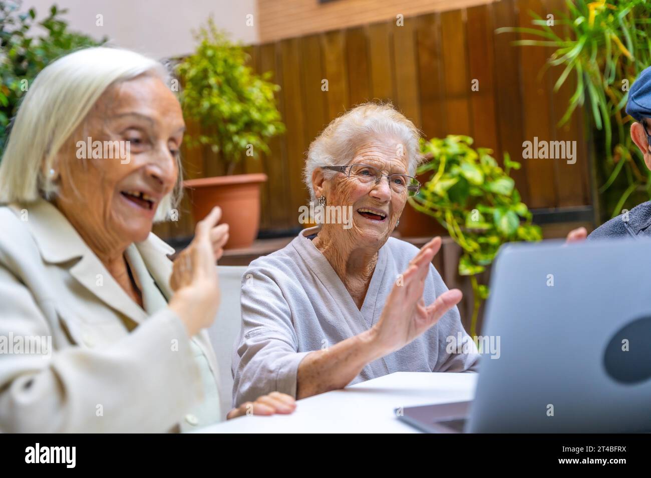 Happy women waving during a video call in a geriatric. Introducing technology to seniors Stock Photo
