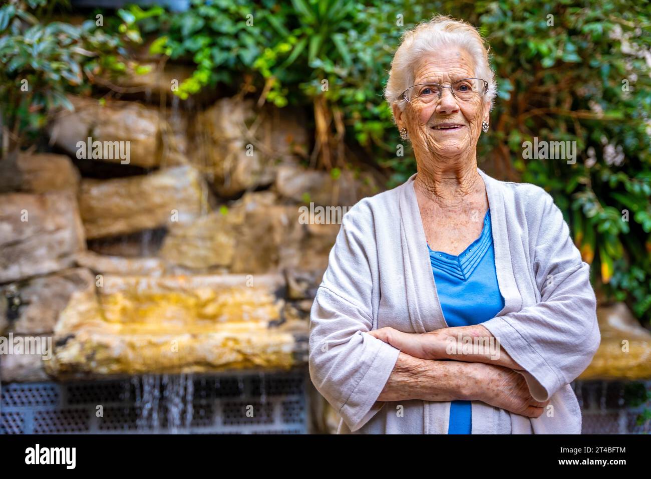 Smiling elder woman looking at camera and smiling in the garden of a nursing home Stock Photo
