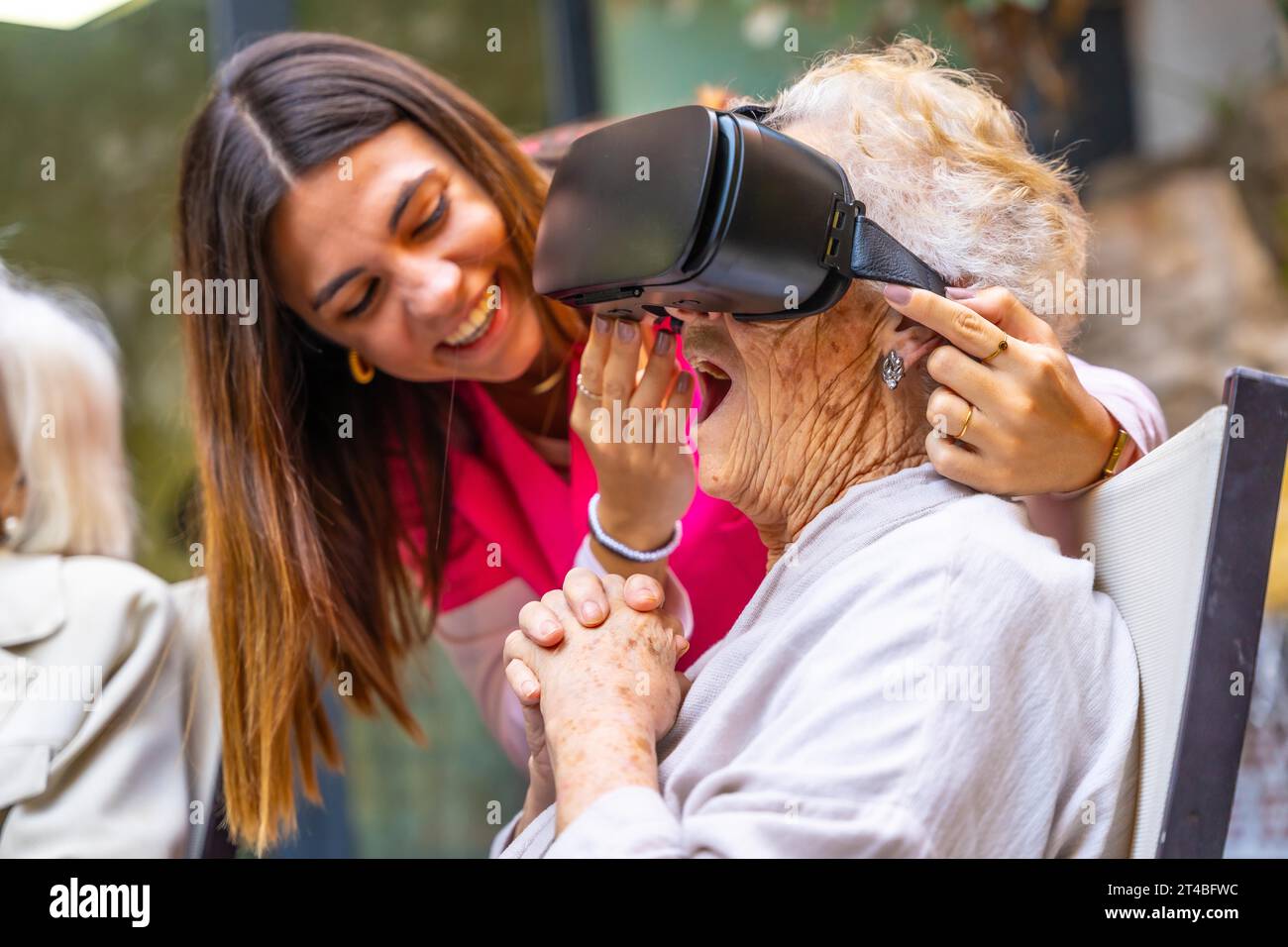 Nurse next to an amazed old woman using virtual reality goggles in a geriatric Stock Photo