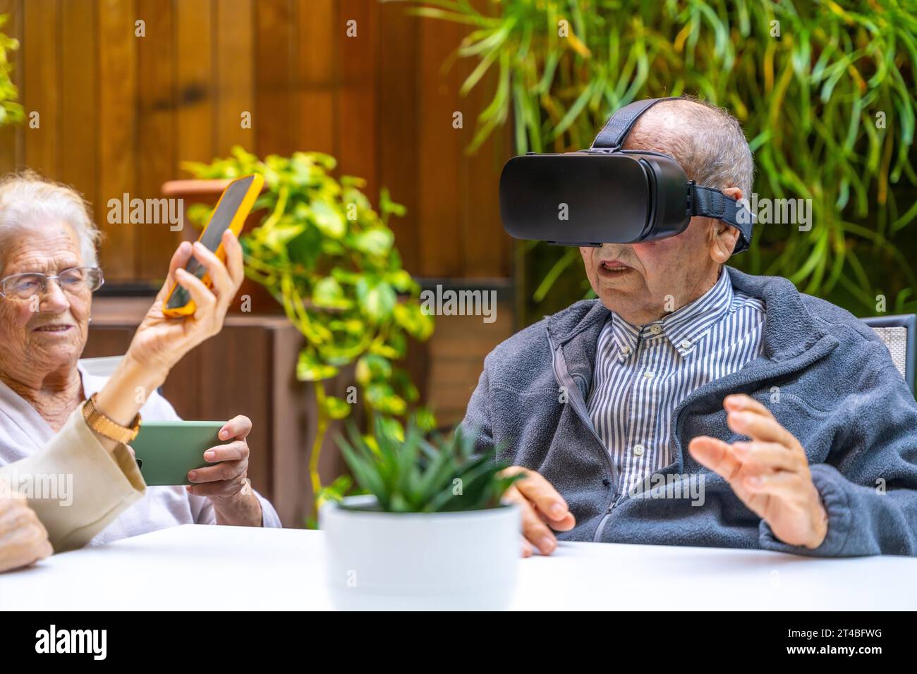 Virtual reality experience for elder people in a geriatric sitting on a garden Stock Photo
