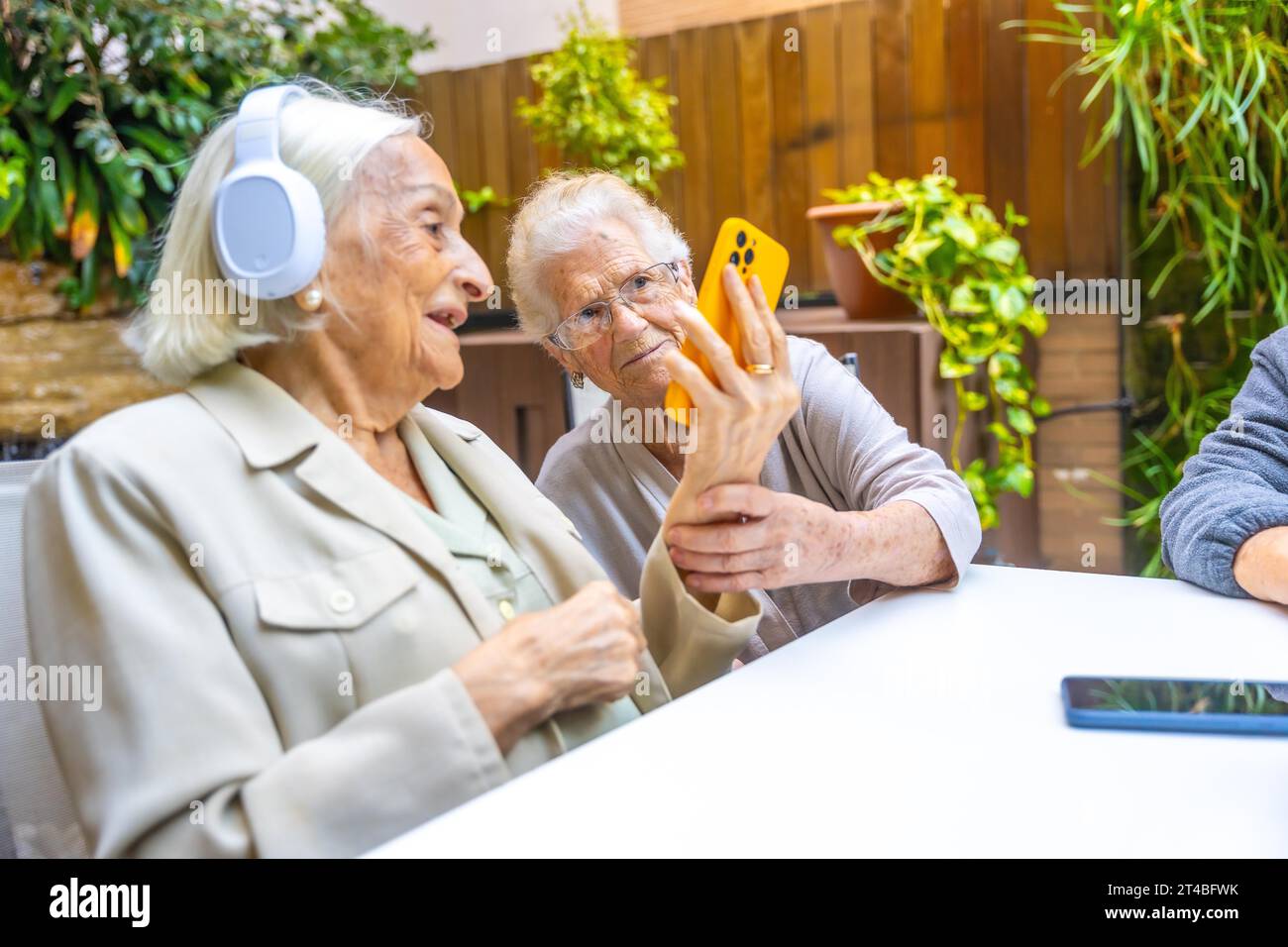 Seniors listening to music with mobile and headphones in a geriatric Stock Photo