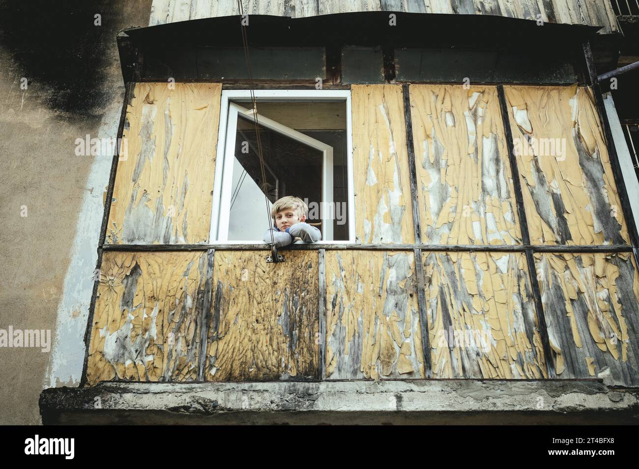 A boy looks out of the window of a flat of a building in danger of