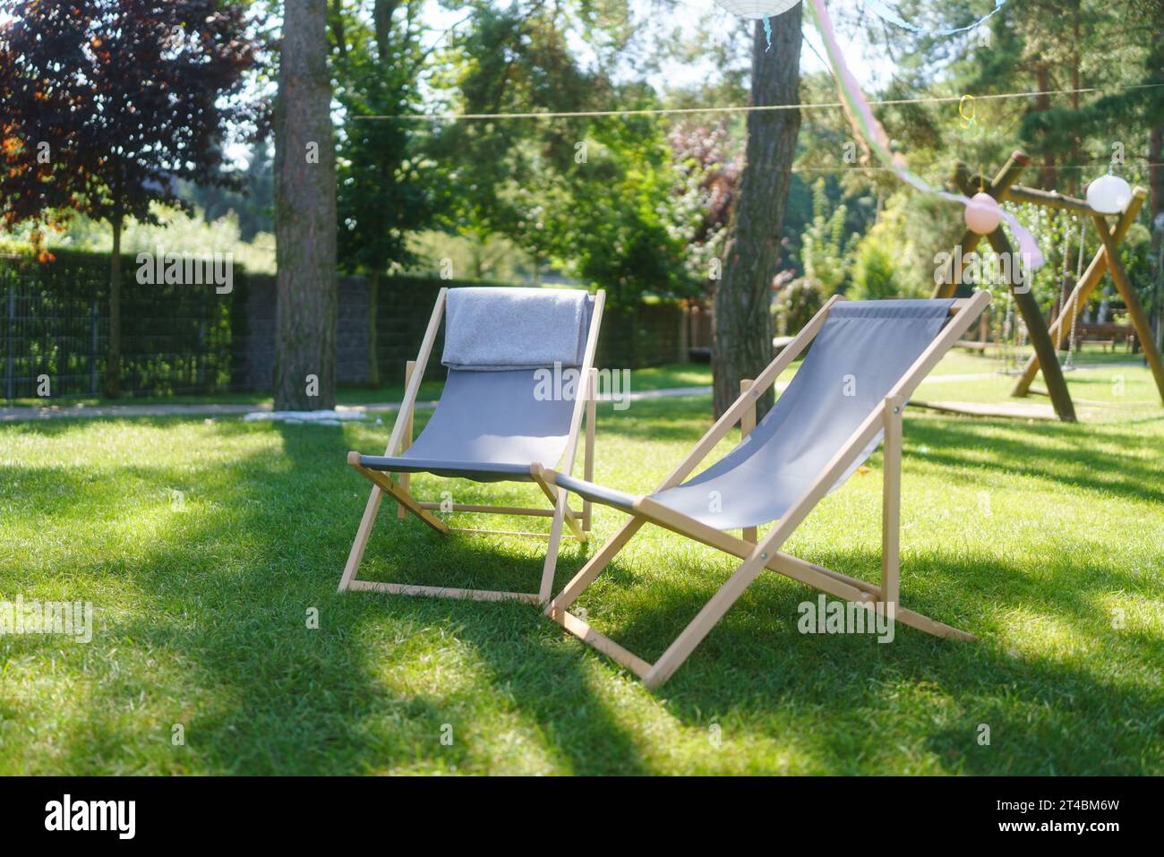 Garden loungers in the garden, in the shade under the trees. Outdoor garden furniture. Stock Photo