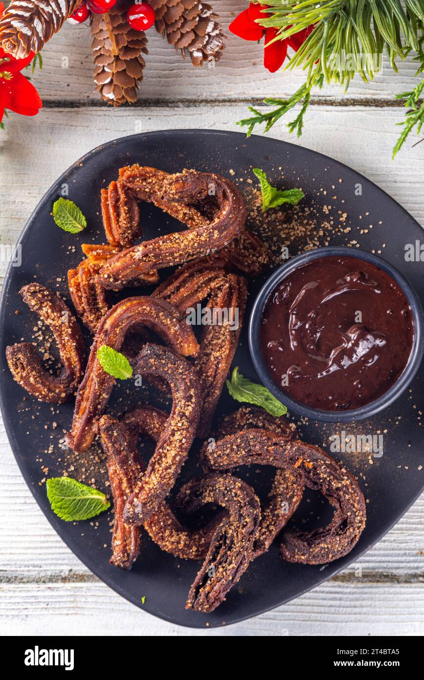 Winter Christmas gingerbread churros dessert, Spanish, Mexican street food fritters fries donuts, with cinnamon, sugar powder and chocolate sauce Stock Photo