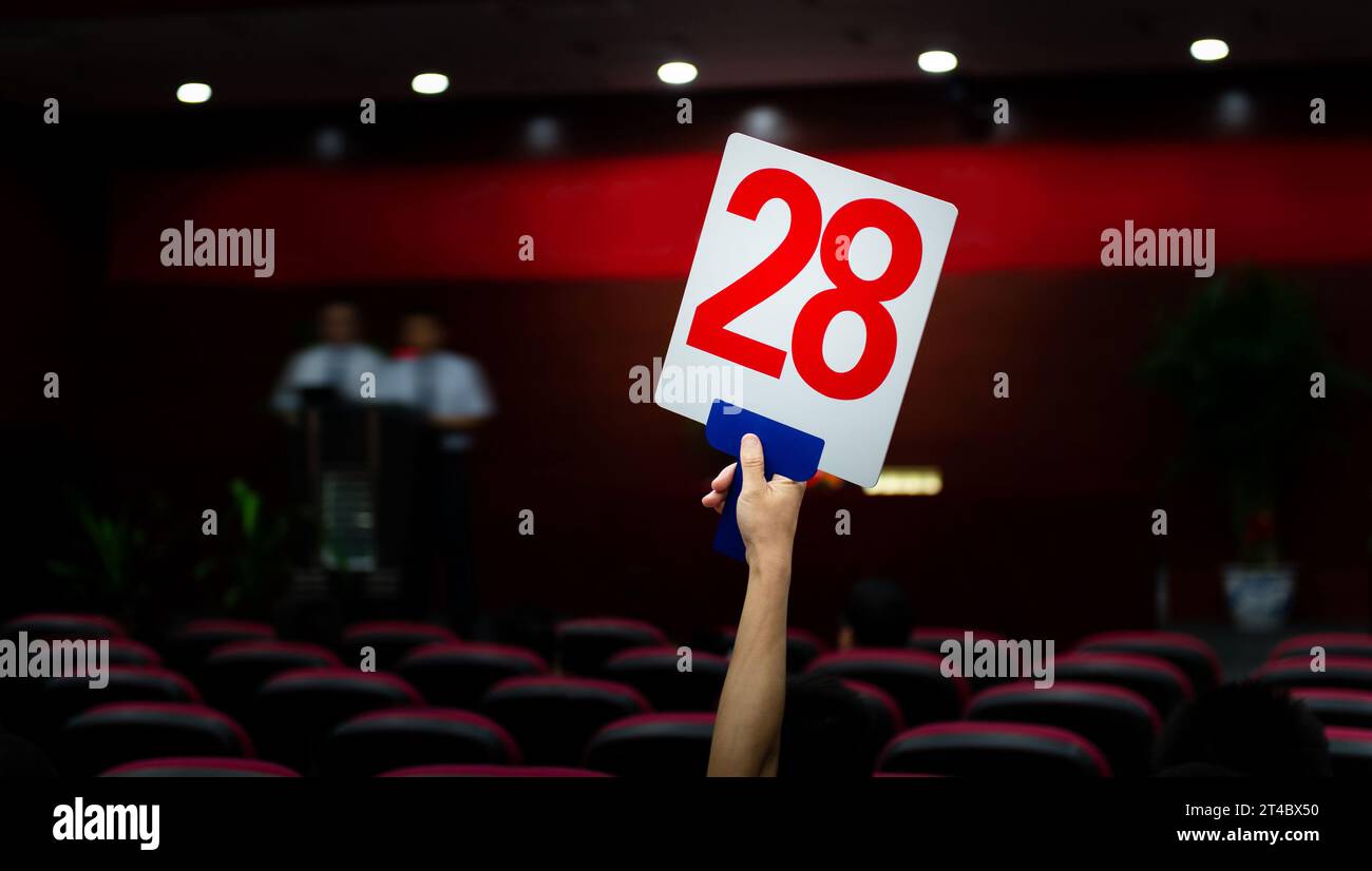 People holding up customer number pacing a bid Stock Photo