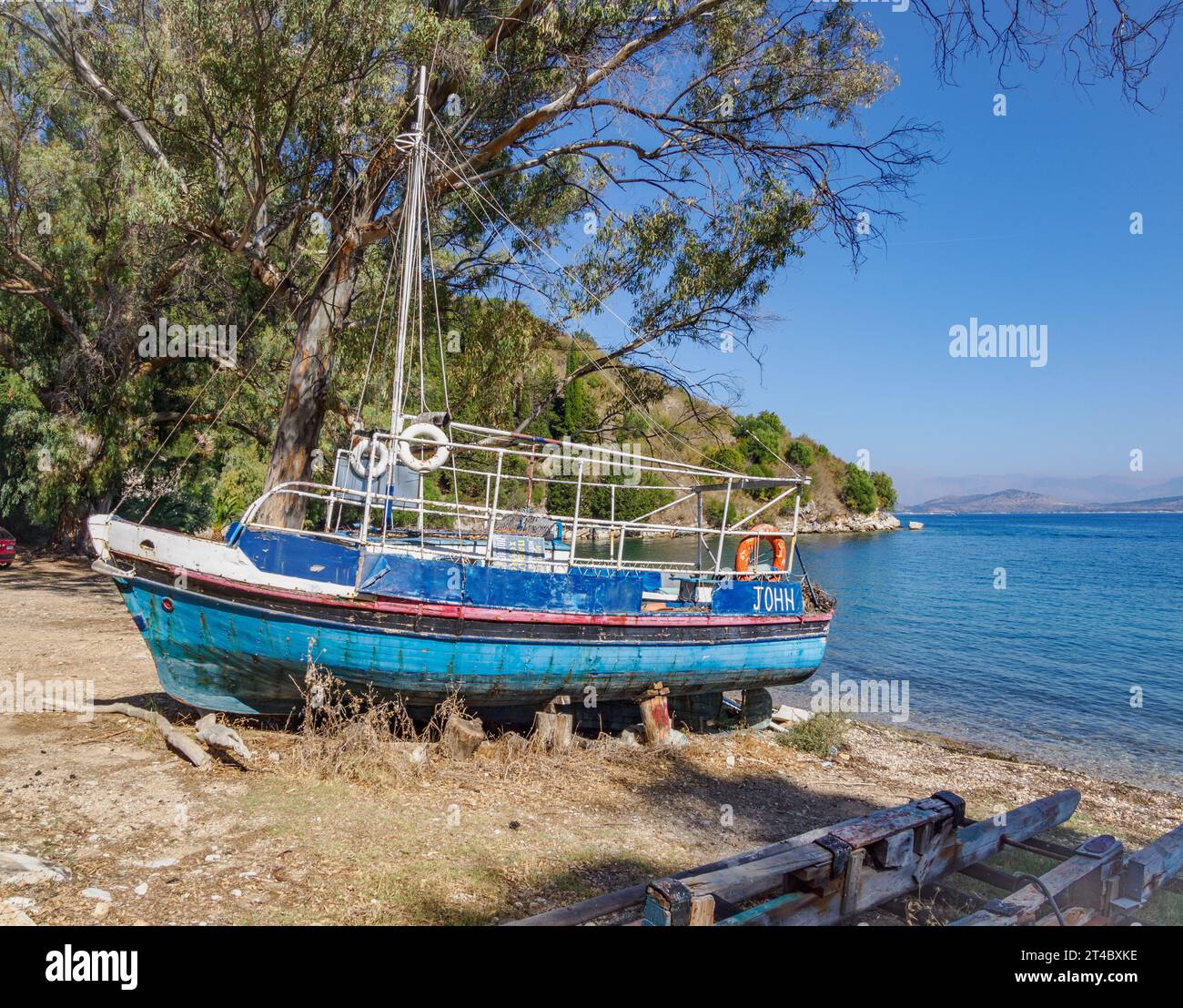 Beached pleasure boat The John at Chouchoulio beach a quiet cove on the north-east coast of Corfu in the Ionian Islands of Greece Stock Photo