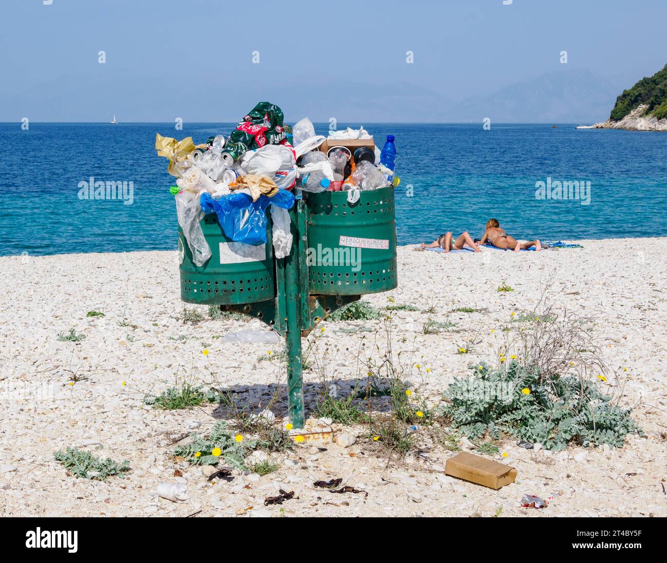 Overfilled litter bins on a clean beach on the north east coast of Corfu Greece Stock Photo