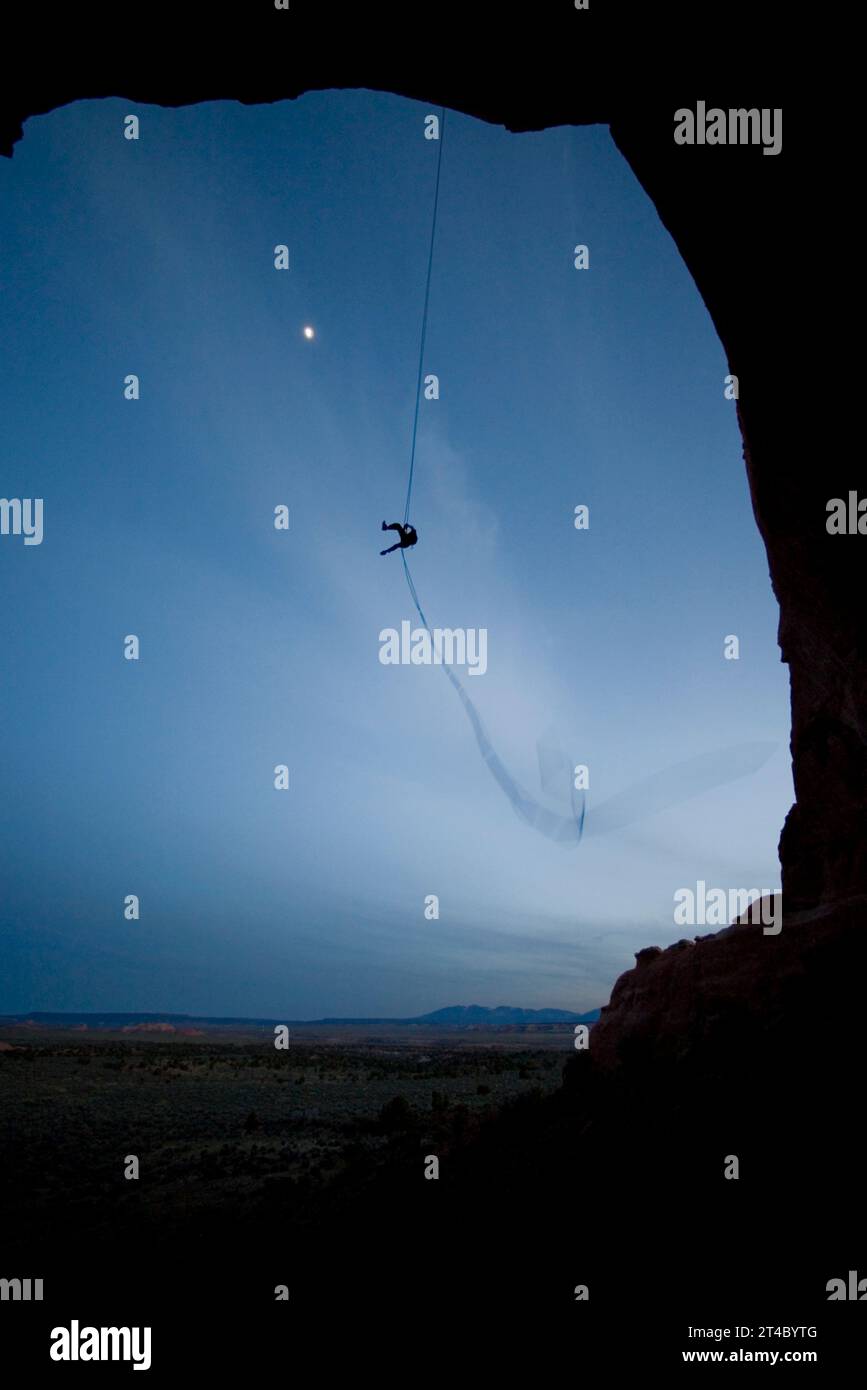 Person swinging on a rope swing off of a rock formation near Moab, Utah. Stock Photo