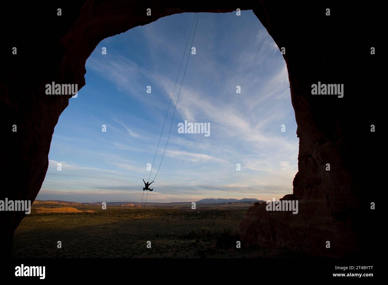 Person swinging on a rope swing off of a rock formation near Moab, Utah. Stock Photo