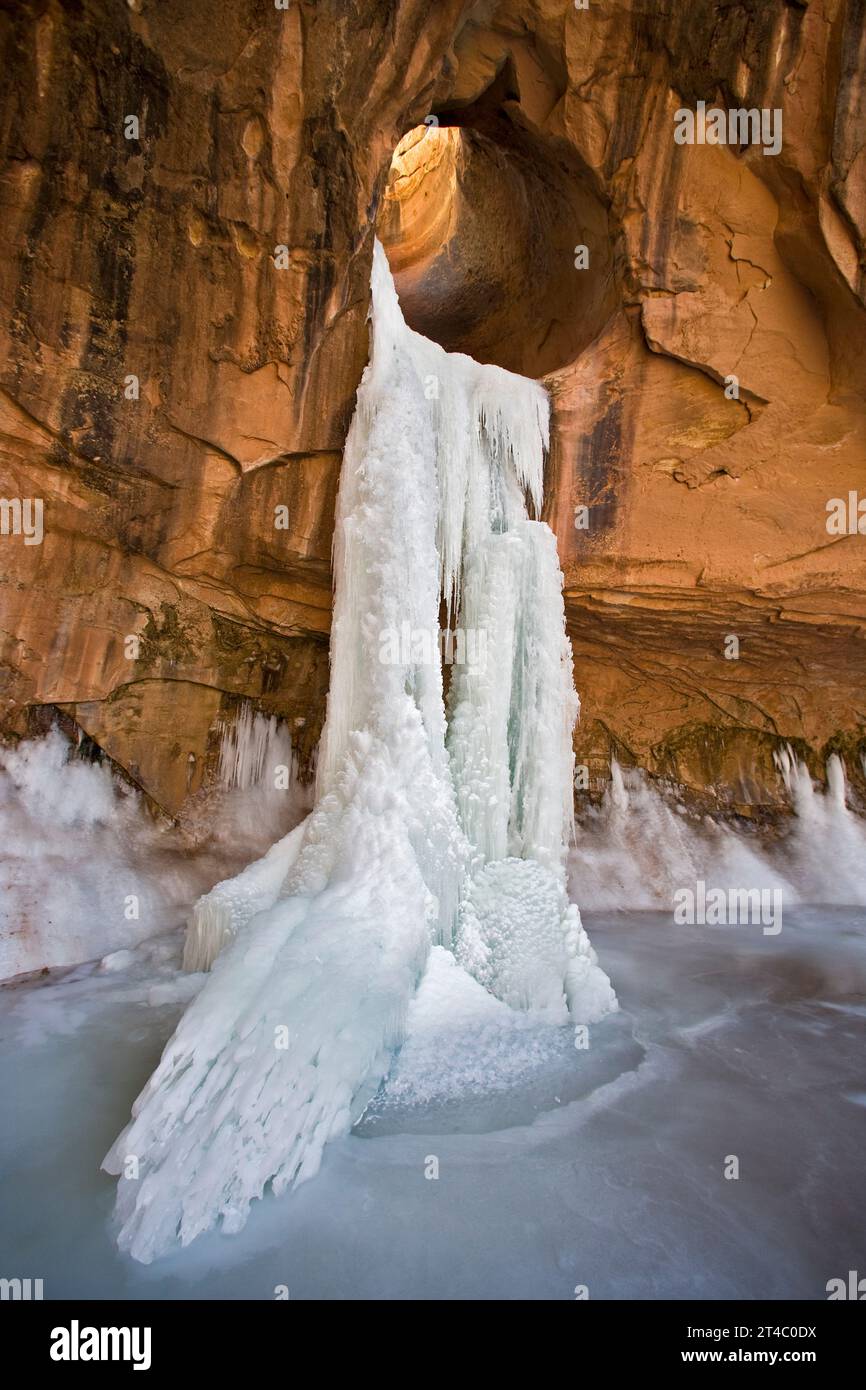 Frozen waterfall coming through a sandstone arch in Utah. Stock Photo
